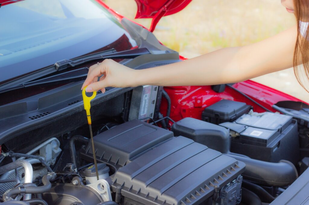 The girl checks the oil level in the car, close-up