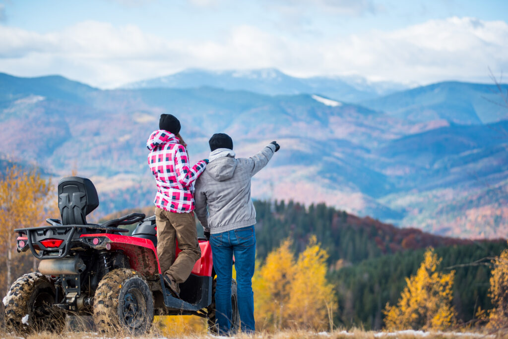 Happy couple on red four-wheeler ATV in mountains.